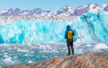 Environmental Concept - A Man Hiker looking at melting Ginat  glacier - Knud Rasmussen Glacier near Kulusuk - Greenland, East Greenland