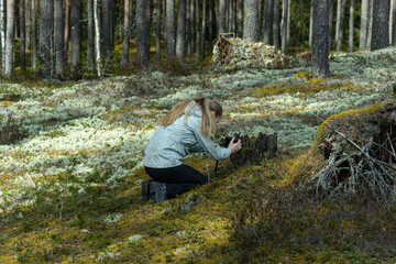 Fototapeta premium A woman takes a picture of forest nature with a camera