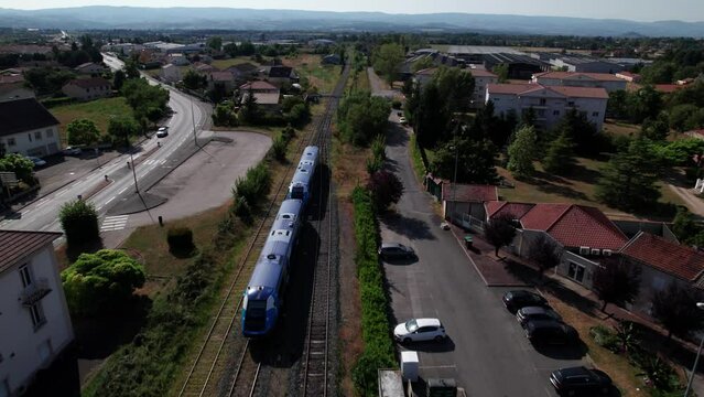 drone shot over a regional train leavig the train station in french countryside, loire department, auvergne rhone alpes region, france