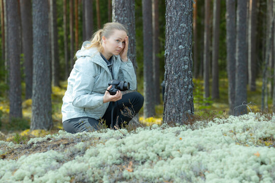A woman takes a picture of forest nature with a camera