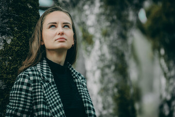 Woman in linden alley in dark clothes with long hair on blurred natural background