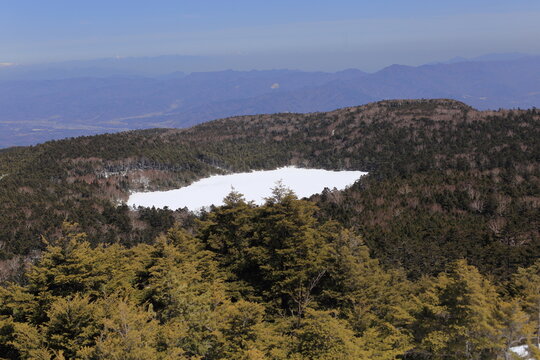 Frozen Shirakoma Pond covered with snow seen from the top of Takamiishi
