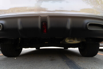Detail of the rear bumper of a vintage car on the asphalt road. Car  in the parking lot.