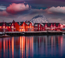 Red wooden houses on Ballstad port, Norway, Europe. Dramatic spring sunset on Lofoten Islands. Calm seascape of Norwegian sea. Traveling concept background.  Life over polar circle. - 784987621