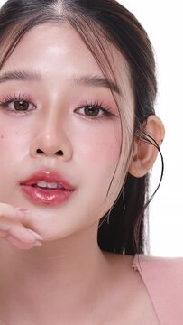 Vertical footage beautiful young Asian woman with healthy facial skin isolated over white background for skincare commercial product advertising. Slow motion shot.