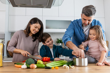 Family with adorable son and daughters gathered in modern kitchen cooking together. Enjoy communication and cookery hobby concept.