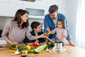 Overjoyed young family with son and daughter have fun cooking diner or lunch at home together,...