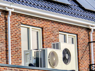 air source heat pump unit installed outdoors at a modern home with solar panels in the Netherlands,...