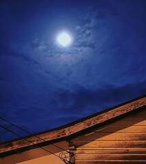 The full moon over the rooftop shines so brightly