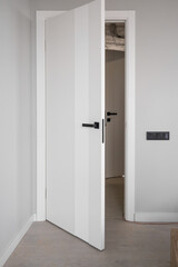 An open white door with a manual one in a renovated apartment. Moving to a new apartment. Doorknob...