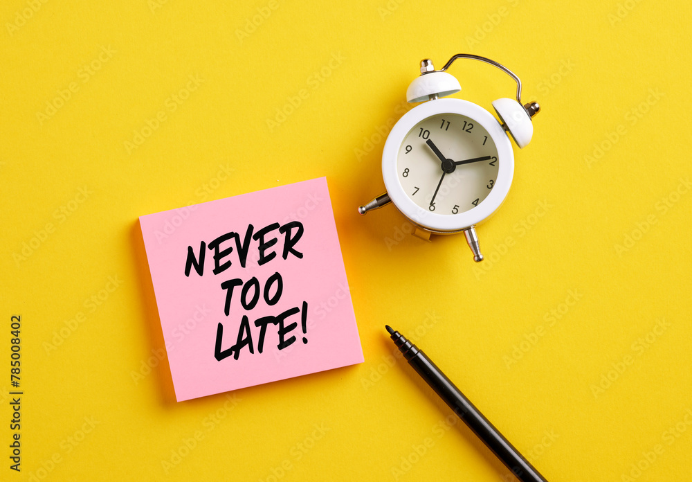 Poster never too late message on pink note paper with alarm clock and pen. motivational message for taking 