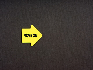 Motivational concept for improvement in business or career. Yellow arrow shaped sticker with the word move on on black background.