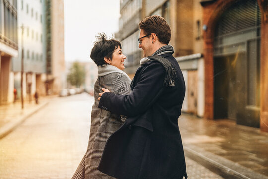 Handsome man and beautiful woman couple falling in love, hugging each other, dancing as they walk around city, having a fun time, lifestyle photo