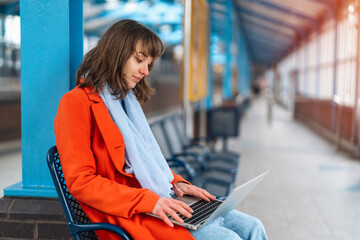 woman at railway station using computer, laptop. Working, studying, shopping, booking online. Enjoying travel concept. 