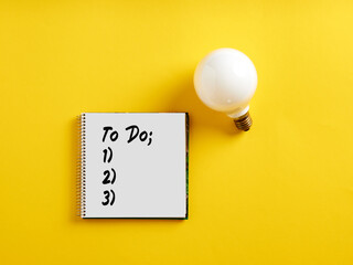 To do checklist on notepad with a light bulb. To do list, tasks to complete for business project or plan concept.