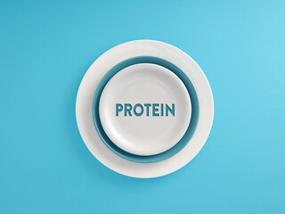 The word Protein written on a plate over blue background. Healthy nutrition concept.