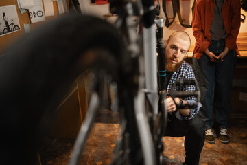 Close-up of a man doing bicycle repair, fixing a bicycle wheel in a garage or workshop. Bicycle...