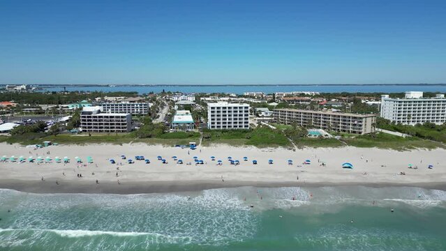 Tourists enjoying the beach with oceanfront hotels, resorts, and condos near Cocoa Beach pier in Brevard County, Florida. 