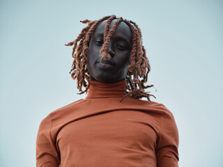 South sudanese man in orange turtleneck looking downwards