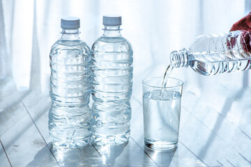窓際のペットボトルと水を注ぐコップ
