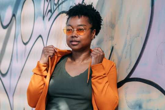 black woman with graffiti posing on wall