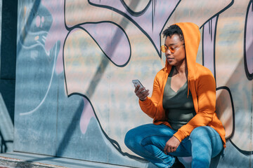 urban woman on graffiti wall with mobile phone