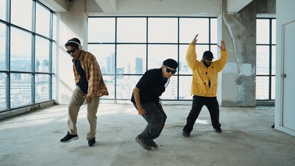 Multicultural hipster group looking at camera while perform break dancing at building with sky...