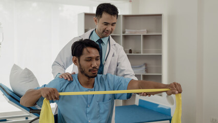 Physical therapist helping a patient while stretching his legs on a bed in a clinic or hospital....
