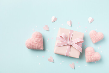Birthday, Woman or Mothers Day greeting card. Pink hearts and gift box on blue pastel table top view. Flat lay.