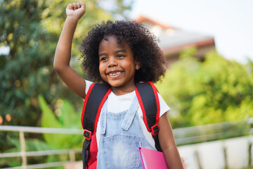 Back-to-school season with african american kid girl on the move with book and colorful school...
