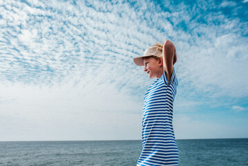 Side view of beautiful girl by sea. Blonde girl in dress enjoying vacation in Canary Islands. Concept of beach summer vacation with kids.