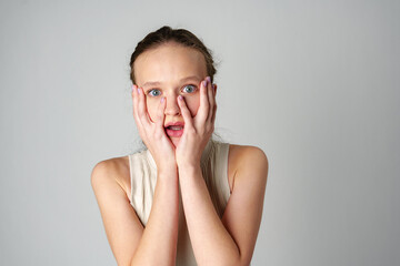 Young Woman Covering Her Face With Her Hands in Fear on gray background