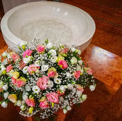 Background with Christian baptismal font and bouquet of flowers