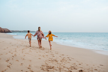 Mother with two kids on beach. Young family enjoying sandy beach in Canary Islands. Concept of beach summer vacation with kids.