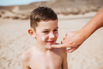 Boy with sunscreen lotion on face. Young boy si protected from sun with sunscreen. Concept of beach...