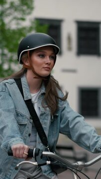 Slow motion view of serious girl in helmet riding bicycle on urban street of Europe