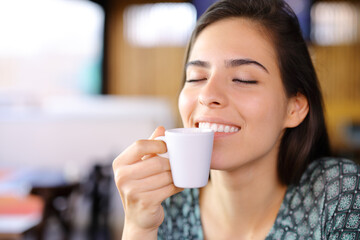 Happy woman smelling coffee in a restaurant nterior - 785030400