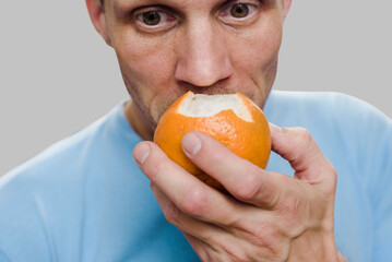 Young man sniffing fresh orange and loosing sense of smell due to virus illness. Taste of...