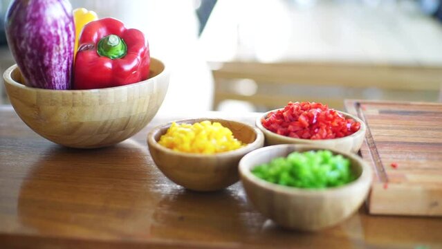 Garden-fresh veggies are meticulously sliced and arranged in a rustic wooden bowl, promising a feast of flavors in this captivating stock footage.