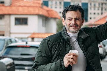 mature man leaning on wall drinking coffee