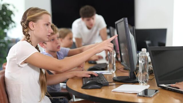 Boy and girl students learn to use computer during lesson in classroom