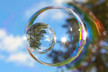 A sphere suspended in a bubble, with rainbow light refracted through soap film, set against a starry night, super realistic