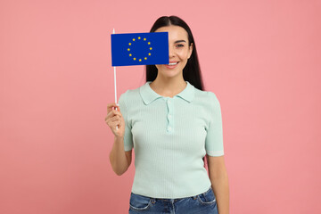 Happy young woman with flag of European Union on pink background