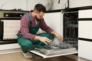 Serviceman examining dishwasher lower rack in kitchen