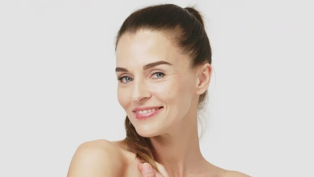Healthy, dry skin care concept, cosmetics and anti-aging plastic surgery. Happy mature middle-aged woman touching face and looking at camera.