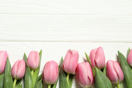 Happy Mother's Day. Beautiful pink tulips on white wooden table, flat lay. Space for text