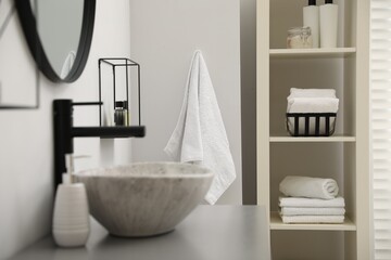 Shelving unit with stacked clean towels in bathroom