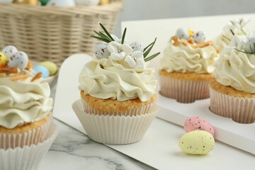 Tasty Easter cupcakes with vanilla cream on white marble table