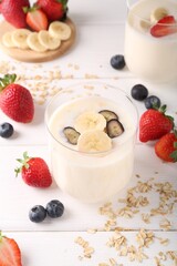 Healthy break. Composition with tasty yogurt, banana and berries in glasses on white wooden table
