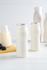 Tasty yogurt in bottles and blueberries on white wooden table